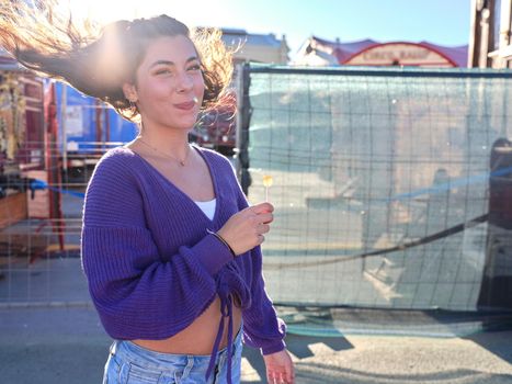 Young woman with vintage clothes turning while waving the hair with a happy expression in the street