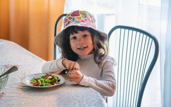 Child girl eats salad at the table. Selective focus. Kid.