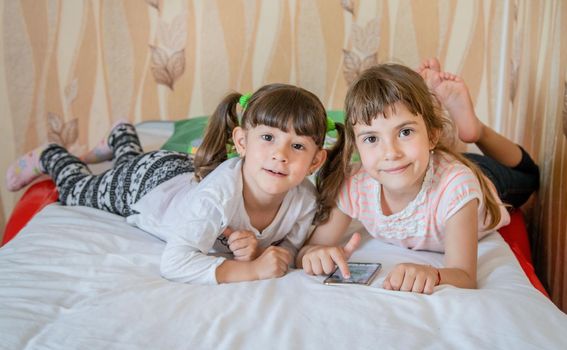 The child is playing the phone on the bed. Selective focus. Kid.