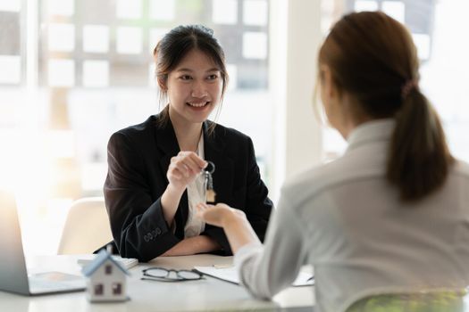 Real estate broker and customer shaking hands after signing a contract: real estate, home loan and insurance concept.