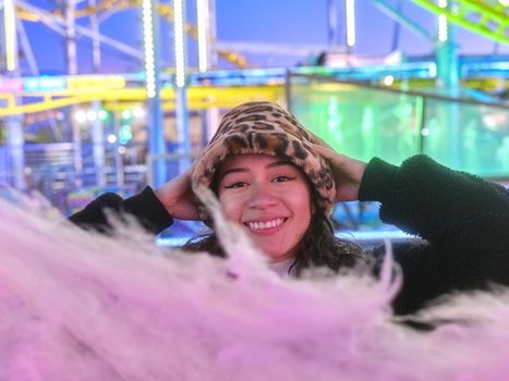 Focus on the face of a woman with a happy surprised expression in front of a cotton candy in a fair