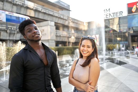 Portrait of two multiethnic friends posing friendly while stanging on a mall in Bangkok