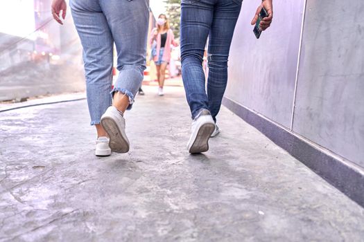 Cropped photo of the Legs of two person wearing jeans walking through a shopping mall in Bangkok