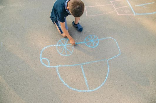 children draw a car with chalk on the pavement. selective focus. nature.