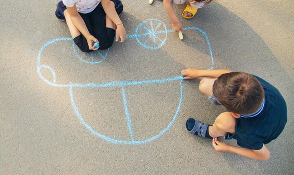 children draw a car with chalk on the pavement. selective focus. nature.