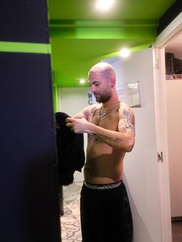 Vertical photo of a caucasian adult man changing in a dressing room of a restaurant