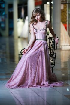 Beautiful blonde woman in a pink evening long dress. Romantic image