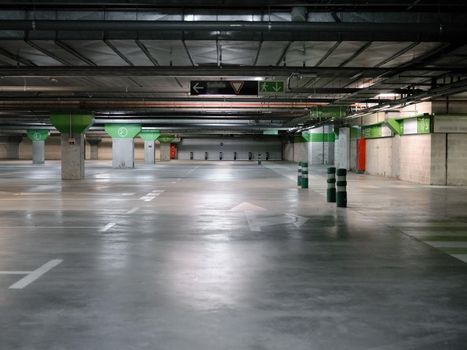 Indoor empty space of a car parking with columns and signs on the floor