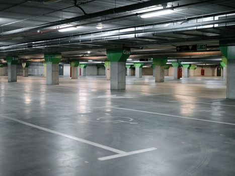 Public car park with columns delimiting the space and handicapped markings on the ground.