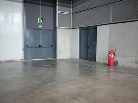 Emergency exit doors of an industrial warehouse next to a fire extinguisher