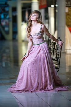 Beautiful blonde woman in a pink evening long dress. Romantic image