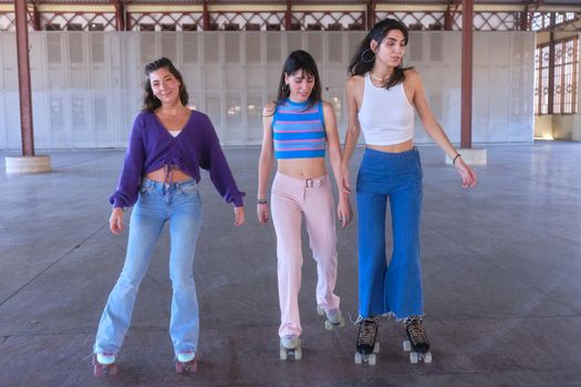 Three slim teenagers skating wearing vintage clothes and classic skates in an urban area