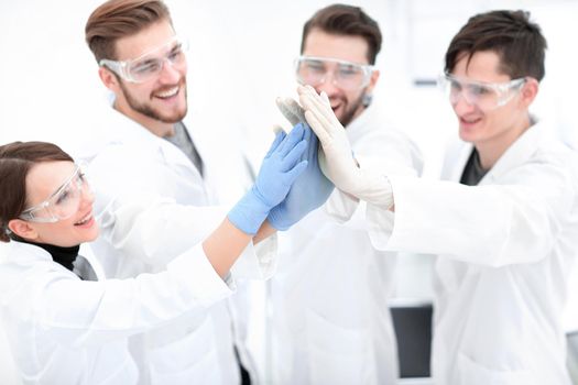 group of scientists giving each other a high five.the concept of teamwork.