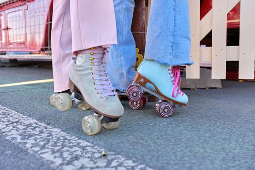 Close up photo of the feet of two chocas with classic skate boots of pastel vintage colors outdoors