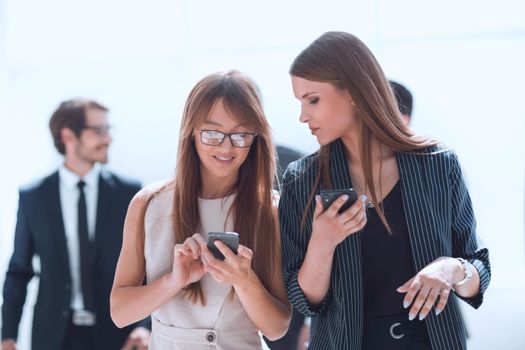 young employees with smartphones standing in the office lobby. office weekdays