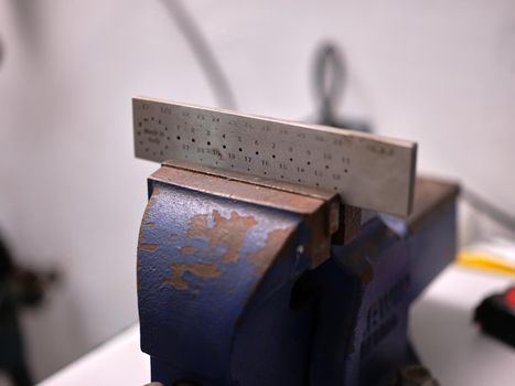 Close up view of a vise holding a wire drawplate in a jewelry workshop.