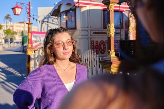 Selective focus on an old fashion style girl looking to a friend outdoors next to a circus parade