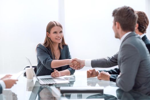 businessman shaking hands with businesswoman sitting at the negotiating table . concept of partnership