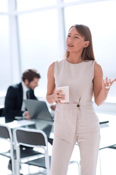 young businesswoman with a glass of coffee discussing something with her colleague