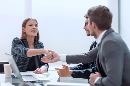 Business people shaking hands over the Desk in the boardroom