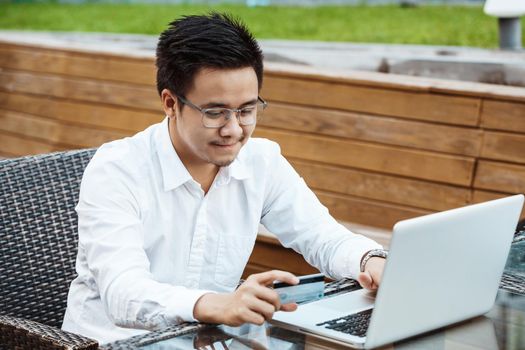 Young Handsome man enjoy shopping online on mobile phone with credit card.