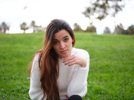 Front view of a young woman in the park looking at the camera feeling missed. Concept of emotions.