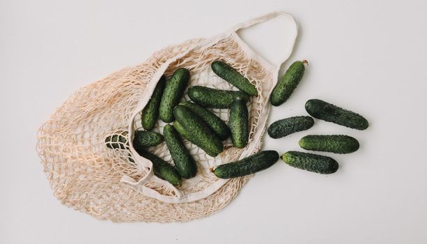 Green fresh cucumbers in a string bag isolated on white background. Concept zero waste. Top view. Flat lay.
