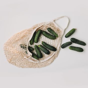 Green fresh cucumbers in a string bag isolated on white background. Concept zero waste. Top view. Flat lay.