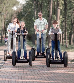happy family riding electric scooters in the Park . The family concept. We go together.