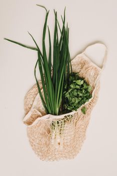 Fresh green onions in eco friendly bag on white background top view, flat lay. Healthy organic food. Zero waste shopping concept.