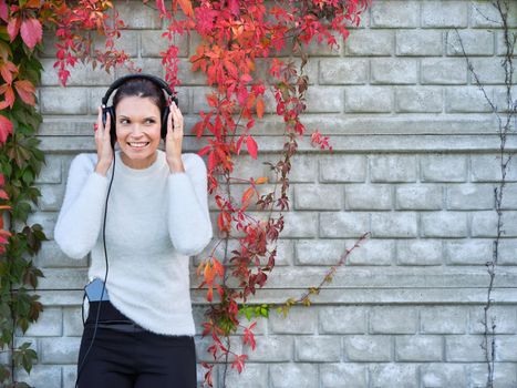 Smiling woman holding the headphones in her head while listening to music with the mobile outdoors