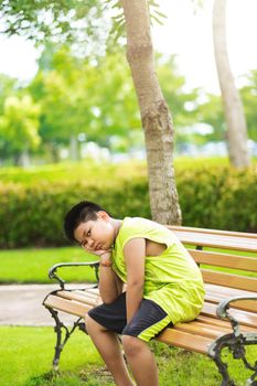 Sport concept - Little sport runner boy sit on the track and take a deep breath. Feel tired and bored.