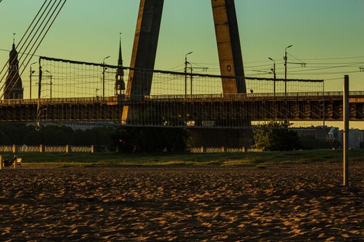 Riga, Latvia- July 17 2020: capital city bridge view at sunrise time, volleyball net nature shine
