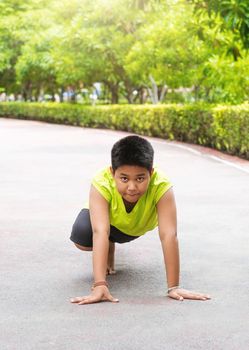 Young Asian boy prepare to start running on track in the garden during day time to practice himself
