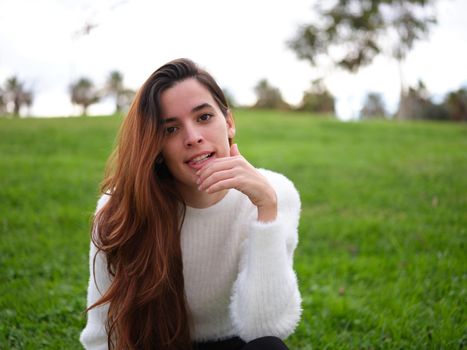 Front view of an angry young woman in the park looking at the camera with her hand on her chin. Concept of emotions.