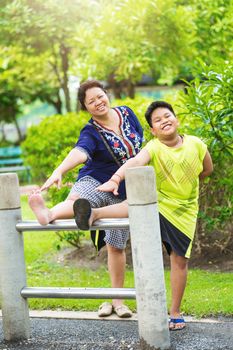 Portrait Asian mother and son exercise in the garden.Sporty woman and child stretch practice in the public park.Outdoor relaxation and happiness family time concept