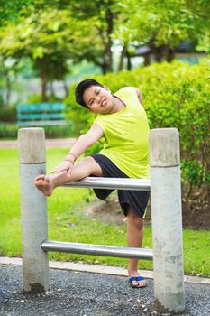 Asian sport boy stretching on iron bar in garden.