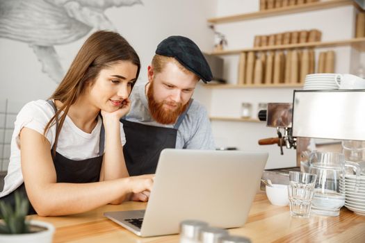 Coffee Business Concept - Satisfied and smile owners look on laptop for online orders at coffee shop