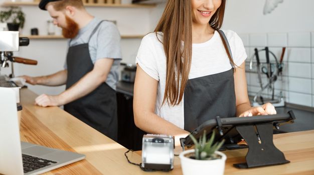 Coffee Business Concept - beautiful caucasian bartender barista or manager Posting order in digital tablet menu at modern coffee shop.