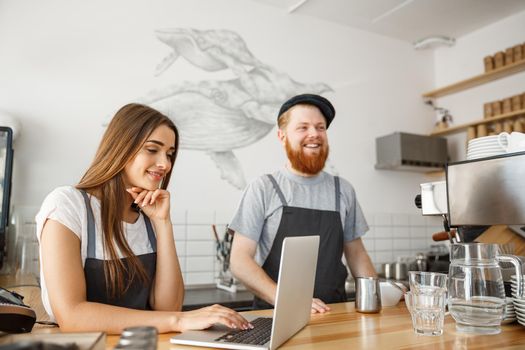 Coffee Business Concept - happy young couple business owners of small coffee shop working and planing on laptop.