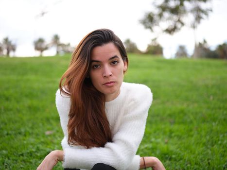 Front view of an angry young woman in the park looking at the camera seriously. Concept of emotions.