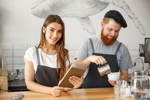 Coffee Business Concept - happy young couple business owners of small coffee shop working and planing on tablet.