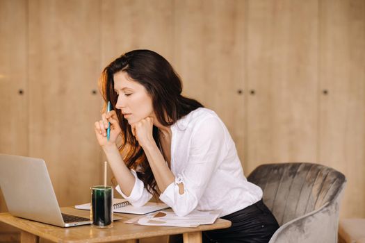 The girl is sitting at a desk in the office and working.