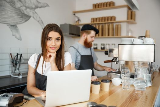 Coffee Business Concept - beautiful caucasian bartender barista or manager working and planing in laptop at modern coffee shop.