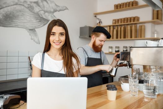 Coffee Business Concept - beautiful caucasian bartender barista or manager working and planing in laptop at modern coffee shop.