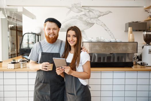 Coffee Business Concept - happy young couple business owners of small coffee shop working and planing on tablet.