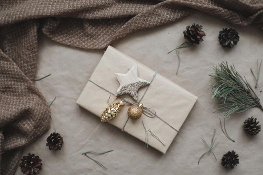 Christmas composition. Gift, fir tree branches, balls on craft paper background. Christmas, winter, new year concept. Flat lay, top view, copy space.