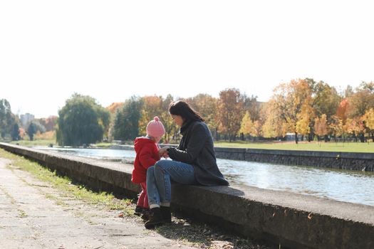 mom and child having fun and walking in the autumn park.