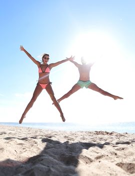 Happy couple jumping on the beach at sunset