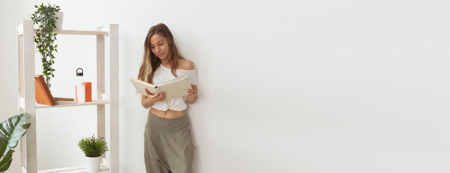 Young woman looking photo album home. Memories and leisure banner white background with copy space